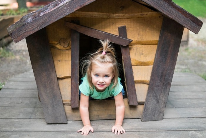 Dziecko siedzi w wejściu do budy.